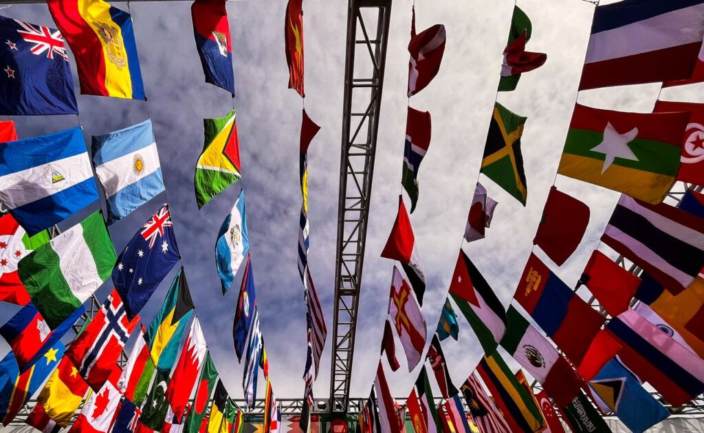 Origin Explained – What Traders Need to Know A dynamic low angle shot of various international flags hanging outdoors against a cloudy sky.